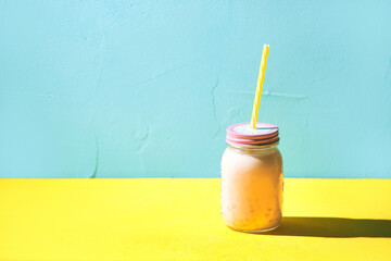 jar of strawberry milkshake with straws on a turquoise background
