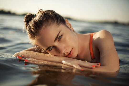 Fashion photo of a girl in the water. Portrait photo of a beautiful girl at the sea. summer fashion portrait of pretty brunette girl posing in blue water. 