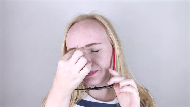A woman rubs his tired eyes with his hands on a white background. The concept of eye fatigue from the computer and fatigue from work. Pain in the eyes and forehead, migraine, eye diseases