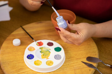 close-up of women's hands dip a brush in silver paint for drawing above palette. indoors free time concept. blogging concept.