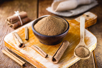 powdered and stick cinnamon on a rustic wooden table. Cinnamomum, used in both sweet and savory foods.