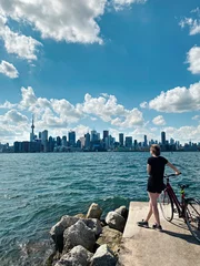 Foto op Aluminium Young woman with bicycle enjoying cityscape view on Toronto city in Canada. Sport summer activity in modern large town. Canadian Toronto islands landmark. Sunny day nature in Ontario. © anoushkatoronto