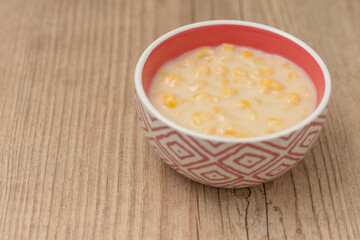 Hominy. Yellow corn with cinnamon in a ceramic bowl. Selective focus. Typical brazilian dessert of june festival in winter - Concept image.