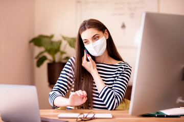 Young woman talking with somebody on her mobile phone while working from home