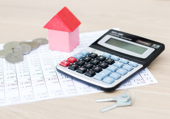 Home insurance concept. On the table is a calculator, a model of the house and keys. Real estate.