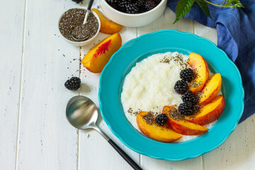 Healthy food for Breakfast, diet food concept. Rice porridge with chia, peach and blackberry in a bowl on a white wooden table. Copy space.