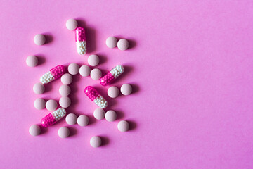 Heap of pills, tablets, capsules on pink background. Drug prescription for treatment medication health care concept wth copy space background.