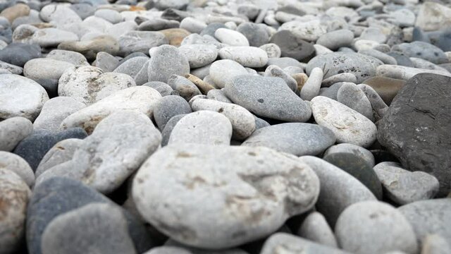 Round pebble beach grey texture stones closeup shallow focus dolly slow right