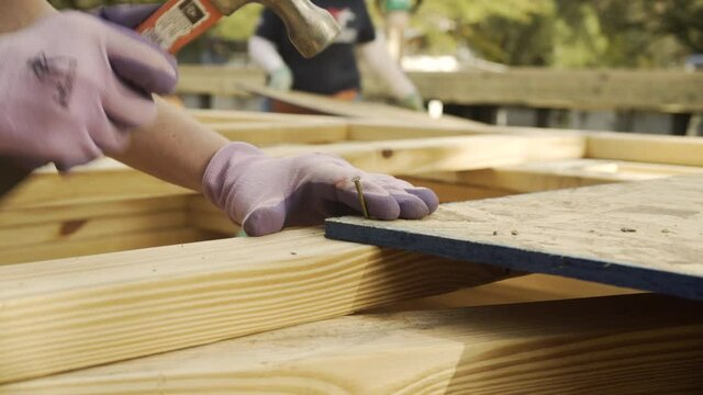 Woman Hammers Nail Into Plywood at Construction Site, Close Up