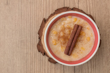 Hominy. Yellow corn with cinnamon in a ceramic bowl. Selective focus. Typical brazilian dessert of june festival in winter - Concept image.