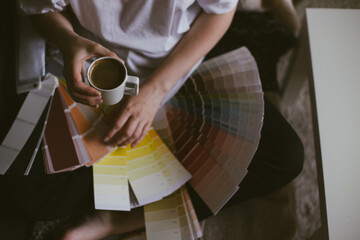 Fototapeta na wymiar Woman choosing paint color from swatches and palette for house renovation and repair.