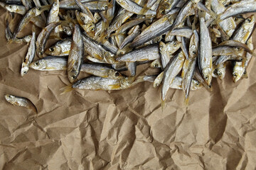 Dried salted fish on crumpled parchment paper background.