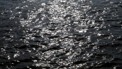 Blurred silhouette sunlight on river surface with water waves and black color for background backdrop 
