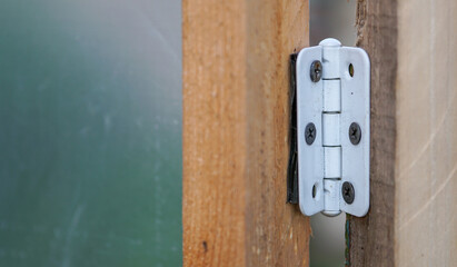 White metal door hinges fixed to wood with black self-tapping screws