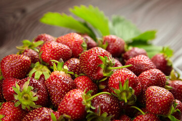 Fresh ripe strawberries with green leaves on blurred wooden background, closeup. Red berries