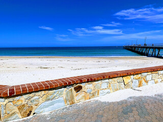 Stretching Sandy beach behind sandstone wall