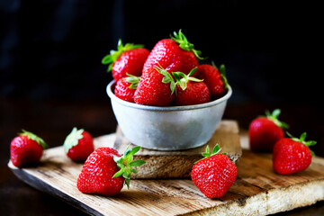 Selective focus. Fresh ripe strawberries in a bowl and on a wooden surface. Selected strawberries of the highest quality.