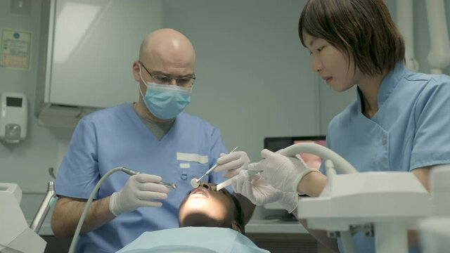 Woman receiving dental treatment, dentist with dental drill