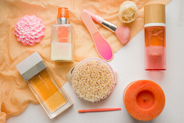 Flat lay composition with cosmetic products pink and orange tones on white background. Female self-care. Top view.