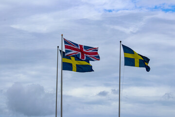 Swedish and british flags isolated against the sky