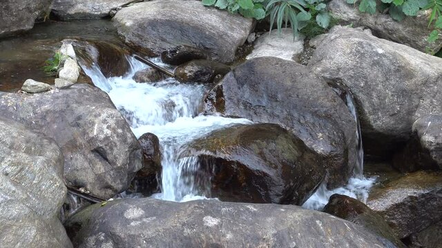 Close footage of waterfall passing through rocks and green vegetation. Footage shot at Jhalong, Dooars, West Bengal - India.