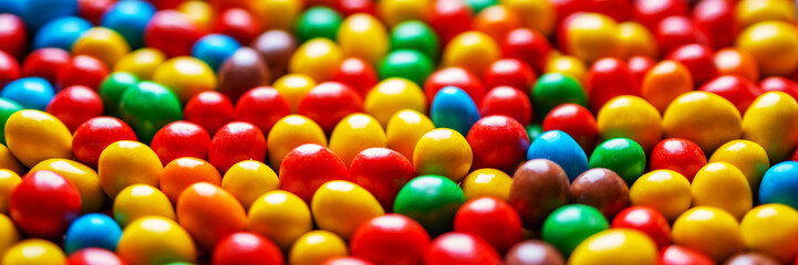 Image of colored round sweets. Background of small multicolored dragees. Closeup. Side vew. Banner.