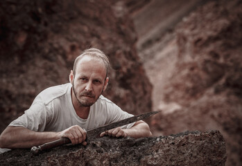 Warlike wanderer in the mountains resting after a battle with a dagger in his hand
