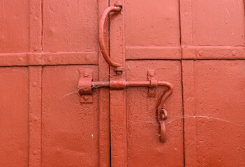 Old door. Reinforced with metal bands. curved handle, deadbolt, rivets. Red paint, cobweb, cracks. Concept of a medieval gate, enchanted entrance.