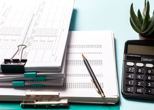 A calculator near documents and pens on the desktop. Business concept