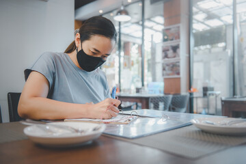 Young asia woman wearing surgical mask in Restaurant. New normal and lifestyle concept with COVID-2019.
