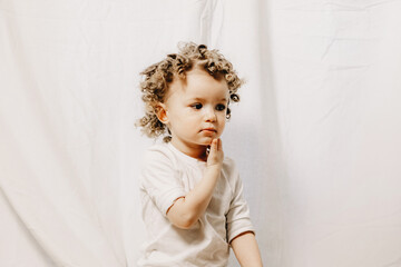 Fototapeta premium Portrait of a little curly girl with freckles dressed in a yellow dress Home family fun parents with baby.