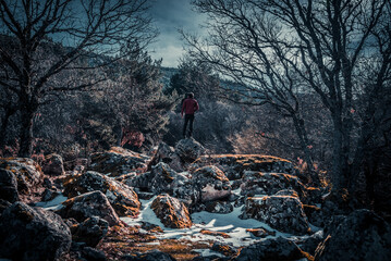 Persona con chaqueta roja en la cima de montaña con nieve en las rocas
