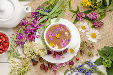Herbal tea in a white cup with flowers. Tea ceremony. Tea with chamomile, with wild rose and clover