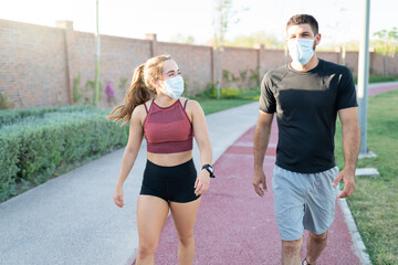 Couple With Face Masks Walking In Park