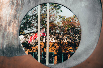 U.S. Flag in city through a hole in statue