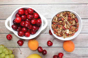Healthy breakfast with ingredients, food for children, summer fruits and berries with granola, grapes, cherries and peaches on a bright table. The concept of a healthy and natural diet, 