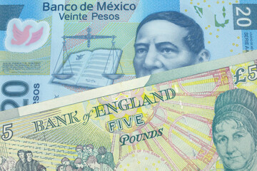 A five pound British pound sterling with a blue, twenty peso Mexican bank note close up in macro