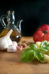 Gnocchi ,italian potato pasta with fresh basil ,garlic ,tomato and olive oil on wood board .Black background.Healthy mediterranean food concept.
