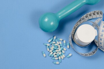 Blue measuring tape around a white bottle of pills,