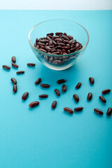 Glass jar with red beans on a blue background.