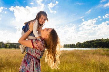Happy mom with daughter against beautiful sky