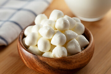 Mozzarella cheese balls in bowl and glass of milk on wooden background