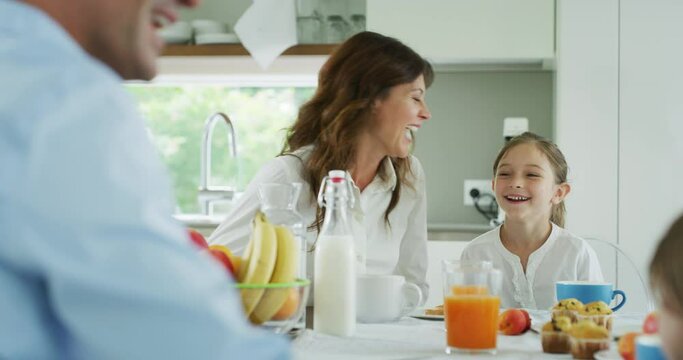 Authentic shot of a happy smiling family is enjoying their time together while having a breakfast in a kitchen at home in the morning.