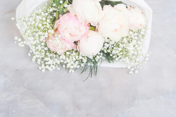 Beautiful bouquet made of white and pink peonies wrapped in white paper. Closeup