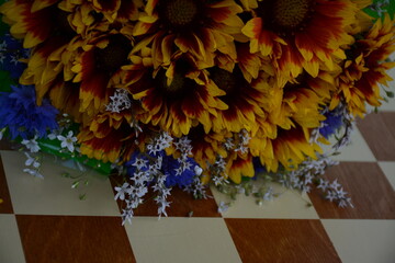 Bouquet of yellow gazania and blue cornflowers on a chessboard
