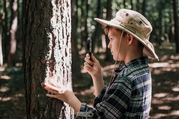 Fotobehang Boy biologist or entomologist studies nature. Scout in the forest. A teenager studies insects. Biology. Geology. Expedition in the forest. © Юлія Мартинюк