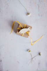 Kommunion, Konfirmation, Firmung, Taufe, Glaube, Religion, religi&ouml;s - Kleines Geschenk mit gelber Schleife und G&auml;nsebl&uuml;mchen auf hellem Grund