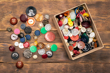 Heap of colorful retro buttons on the wooden flat lay table background.