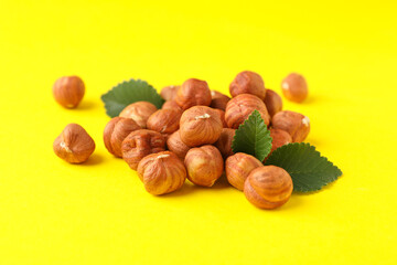 Tasty hazelnuts and leaves on yellow background. Vitamin food