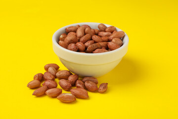 Bowl with peanut on yellow background. Vitamin food